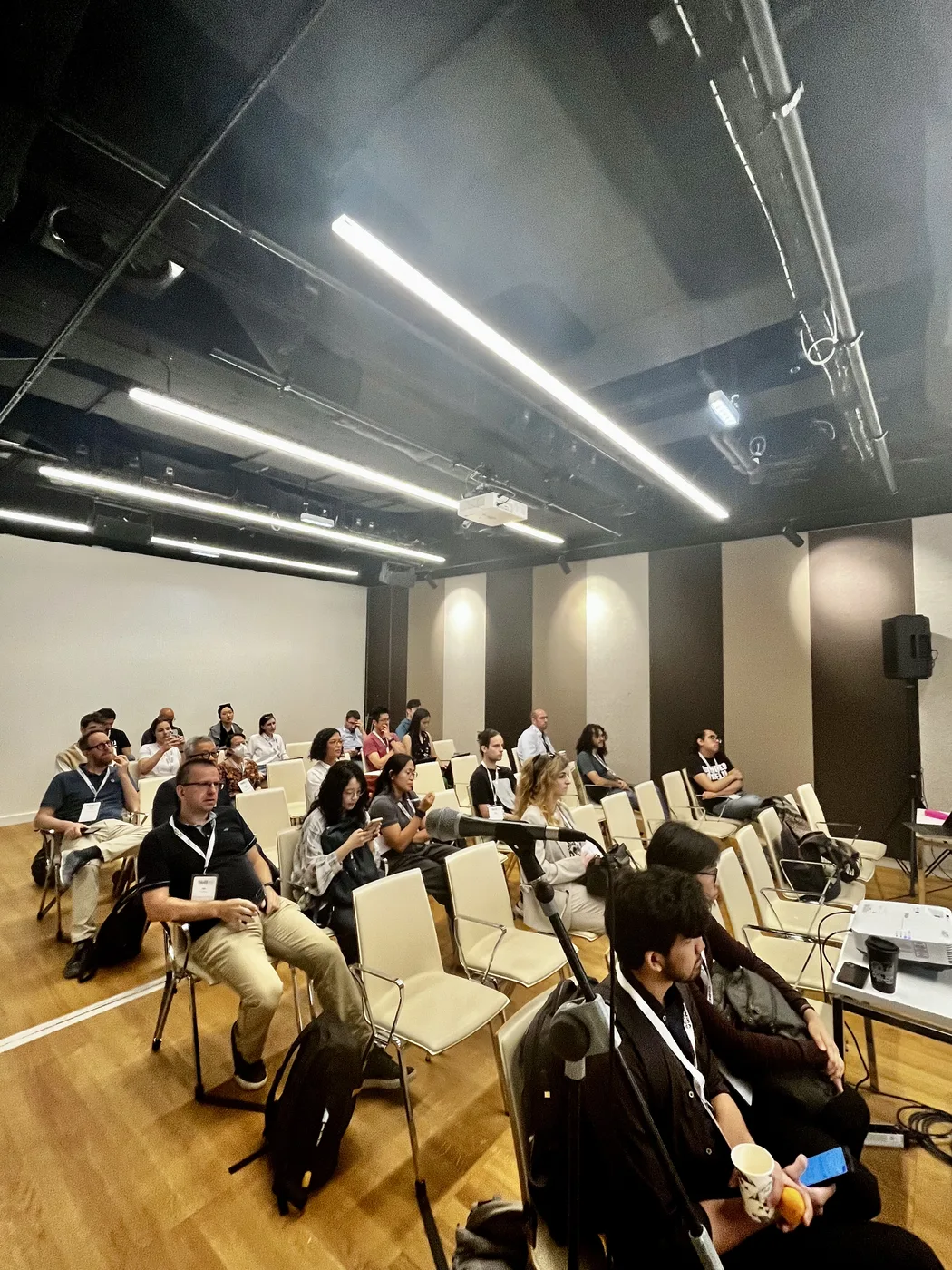 Audience members listening to a crisis language technology presentation at ACL 2025